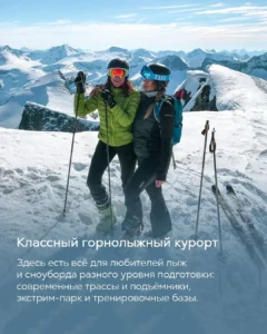Две девушки на лыжном курорте в шлемах и очках позируют на вершине заснеженной горы Красной Поляны