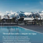 Тёплый открытый бассейн с подогревом на фоне заснеженных горных вершин и шале в Красной Поляне
