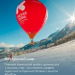 Красный воздушный шар с надписью «Красная Поляна» летит над заснеженными склонами и горами Кавказа