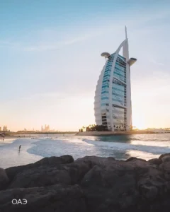 Отель Burj Al Arab в Дубае на закате, волны и скалы на переднем плане — отдых в ОАЭ зимой